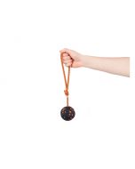 Mano sujetando la cuerda del juguete para perro Non-stop Dog ball on rope, mostrando la pelota con textura naranja y negra.
