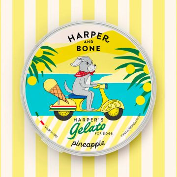 Envase redondo amarillo de helado para perros Harper and Bone sabor piña con ilustración de perro en scooter.